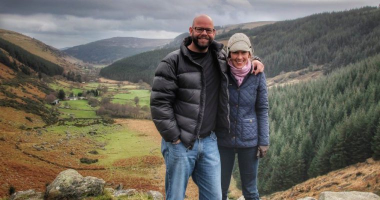 A man and woman standing on top of a mountain in ireland.