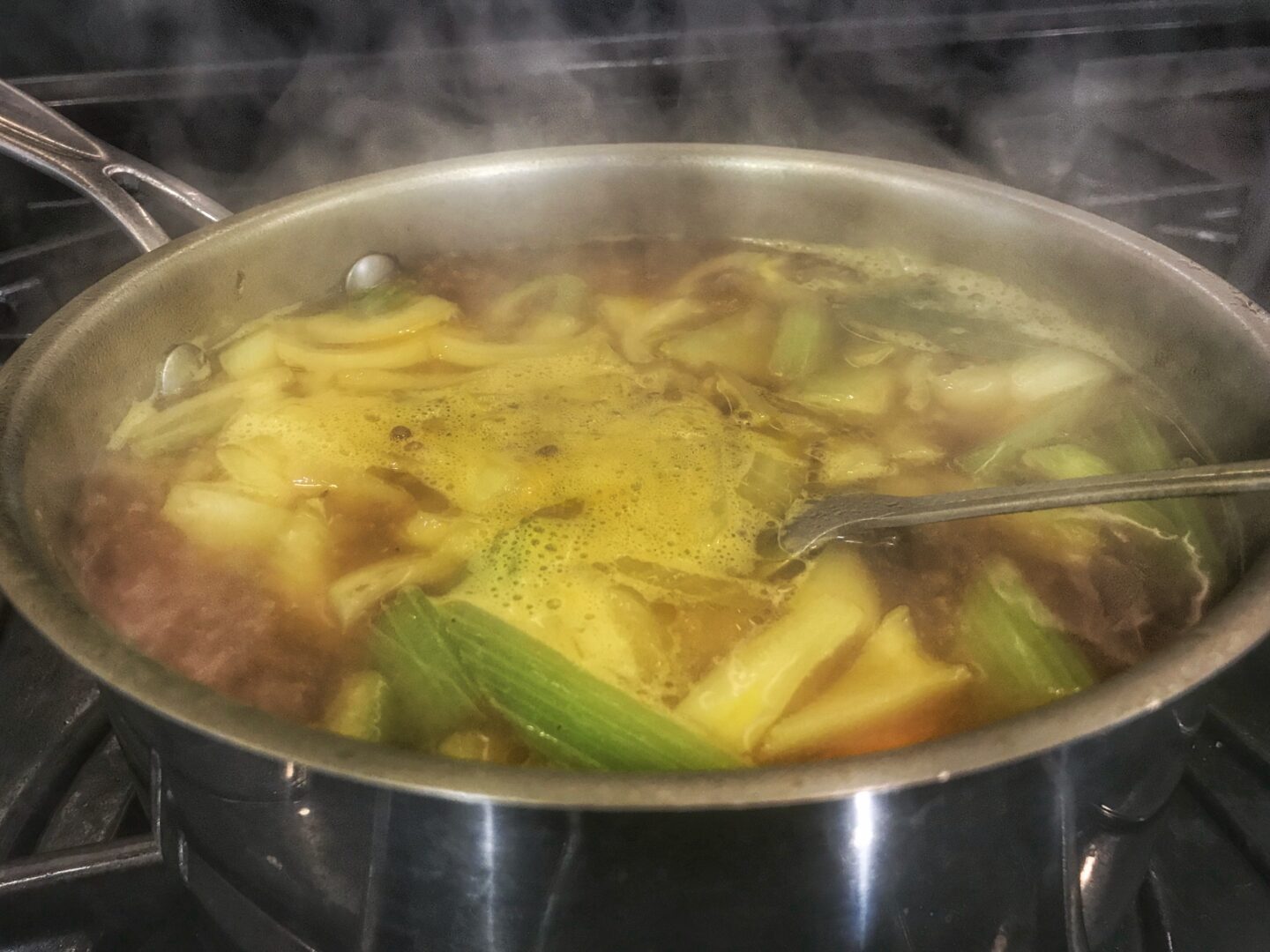 A pot of soup on a stove with steam coming out of it.