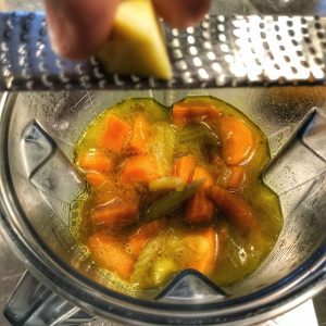 A person is slicing carrots in a food processor.