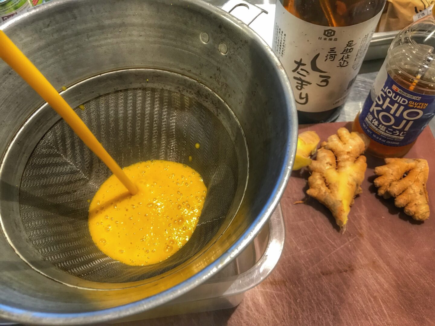 A bowl of ginger juice being poured into a container.