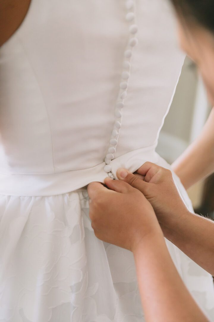 A woman putting on a white wedding dress.