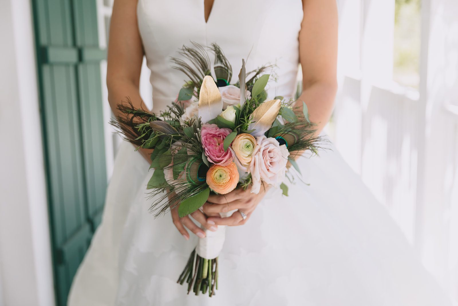 A bride holding a wedding bouquet in front of a porch.