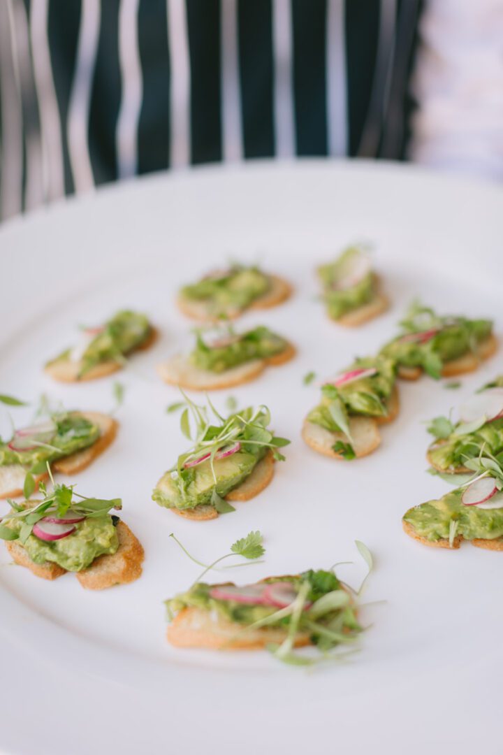 A plate of small appetizers with greens and radishes on it.