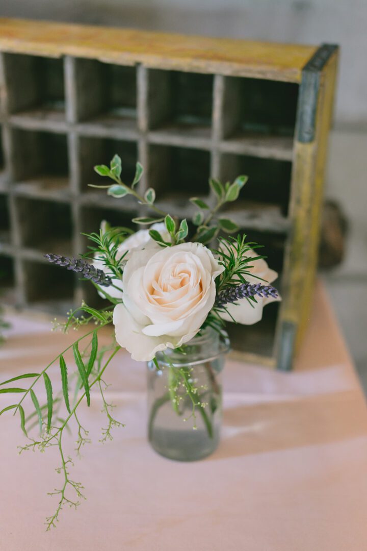 A vase with roses and greenery on a table.