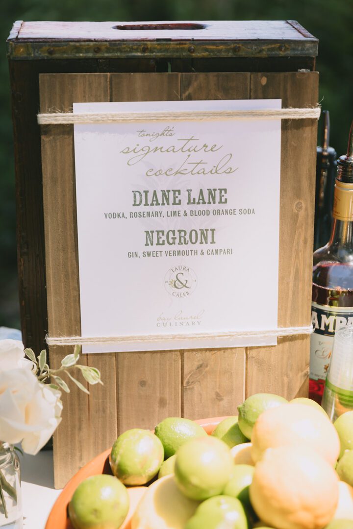 A sign with limes and lemons on a wooden table.