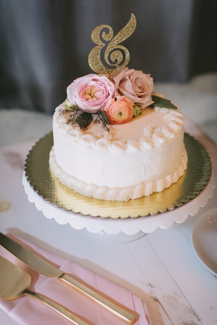 A pink and gold cake with flowers on top.