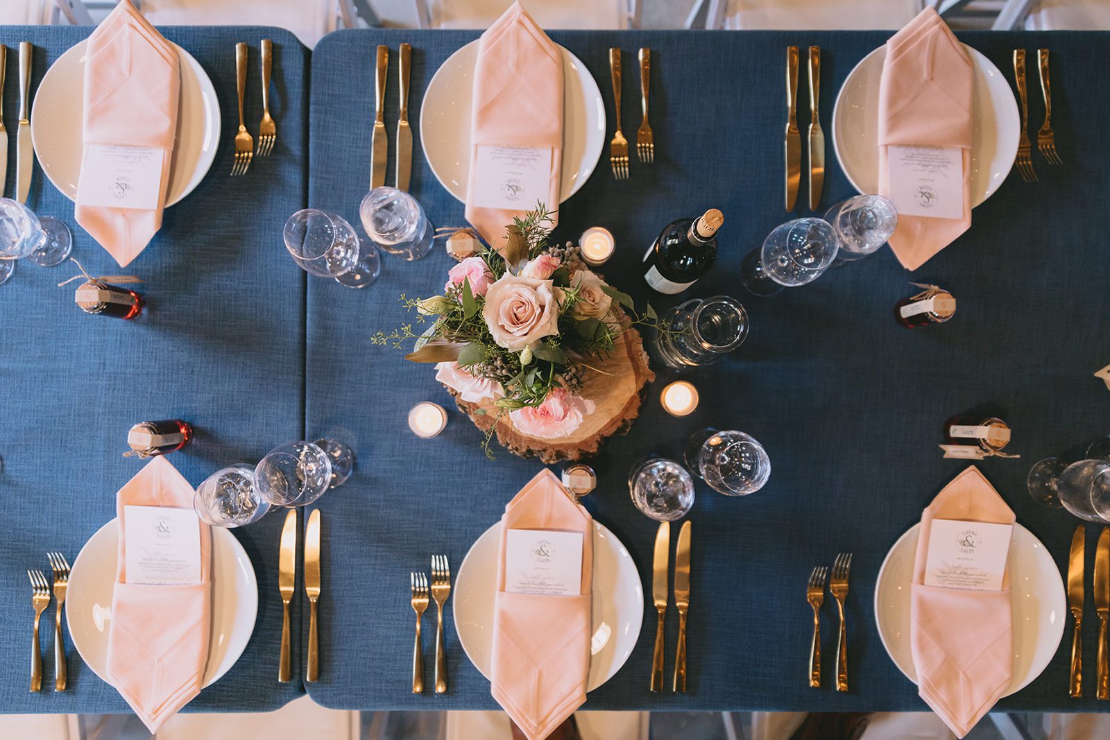 A blue table setting with pink and gold place settings.
