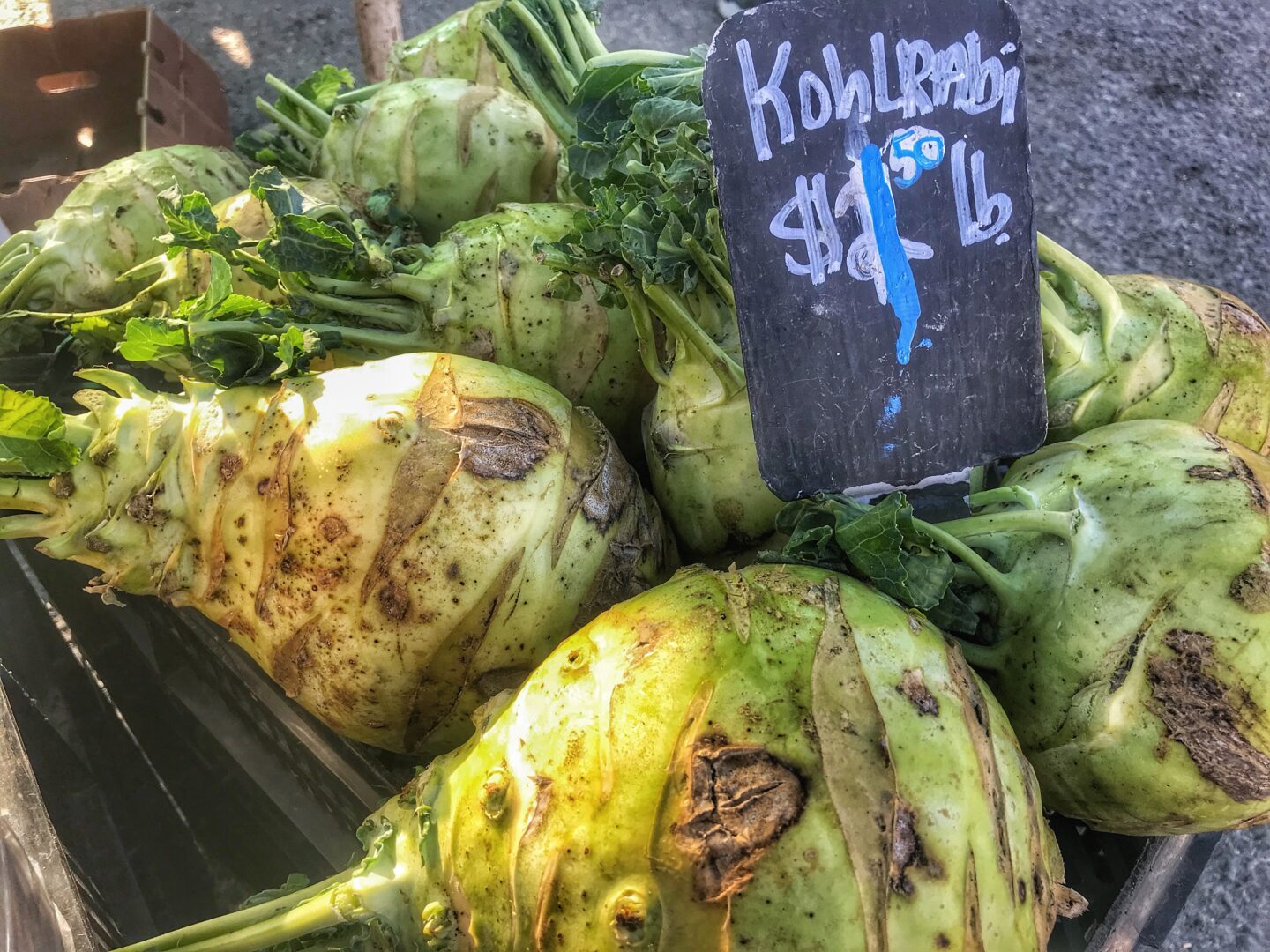 A crate full of green vegetables with a sign on it.