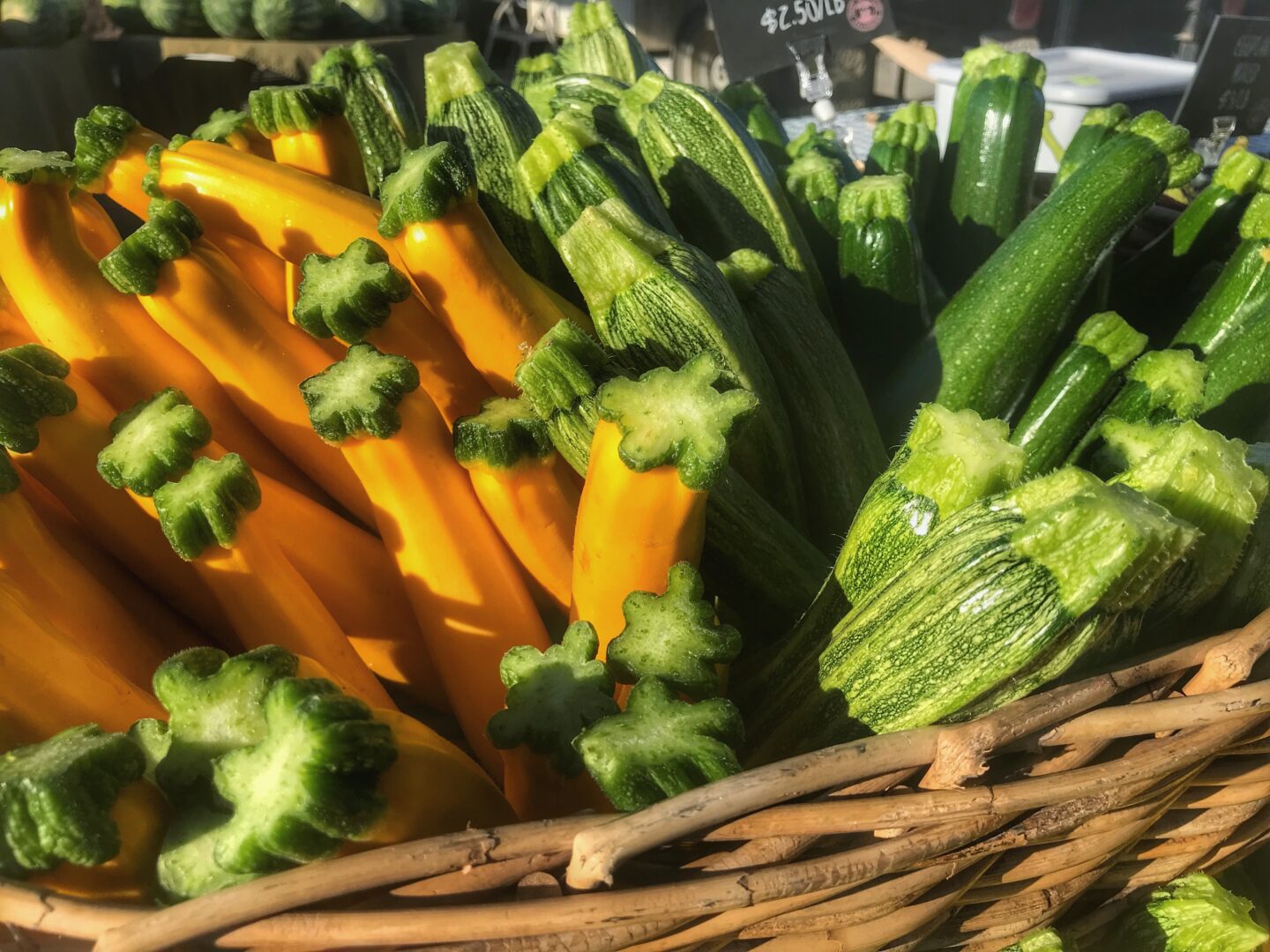 A wicker basket full of zucchini and yellow squash.