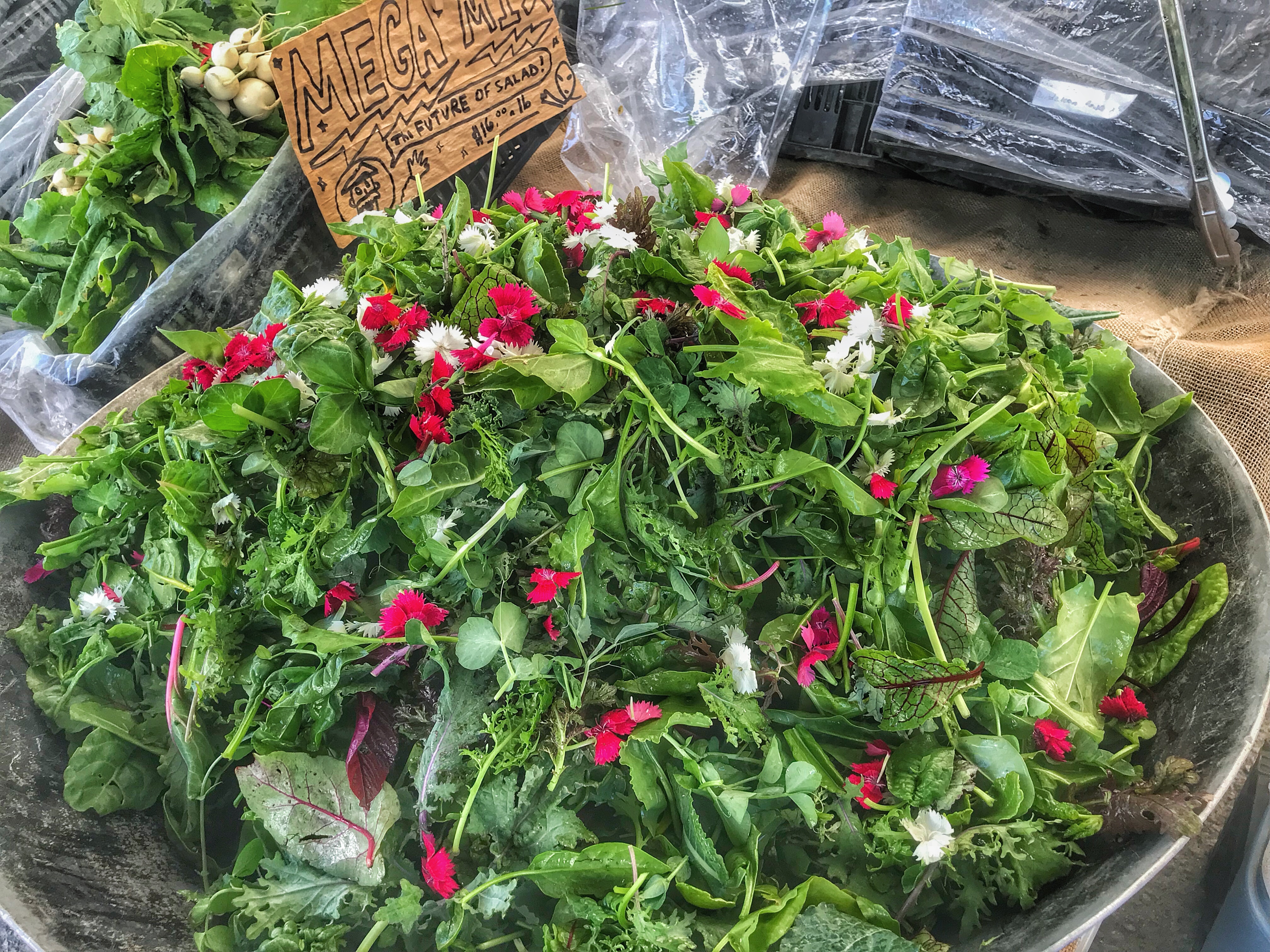 A bowl of greens with a sign on it.