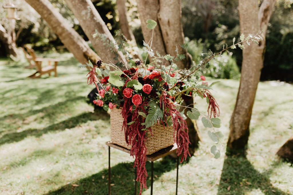 A wicker basket filled with flowers on a wooden stand.