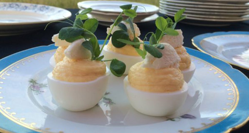 Deviled eggs on a plate with greenery.