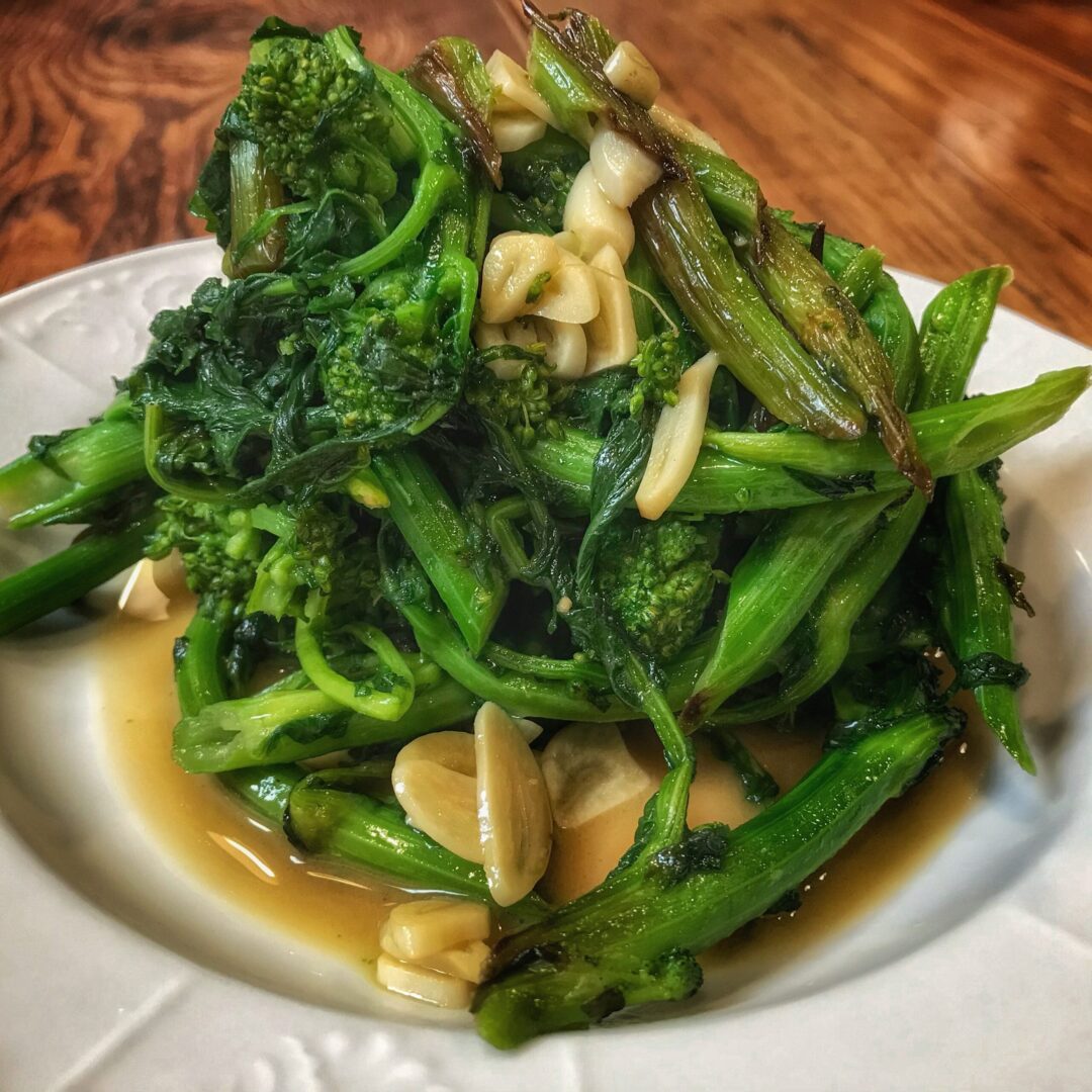 A plate of broccoli and almonds on a wooden table.