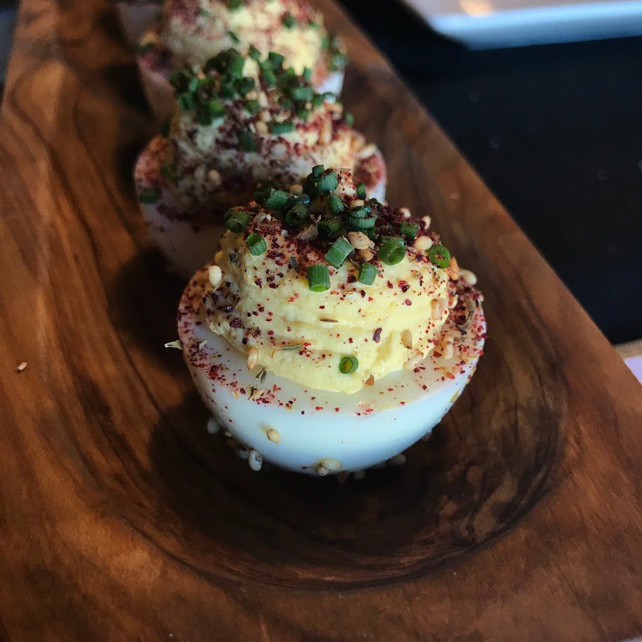 Deviled eggs on a wooden plate.