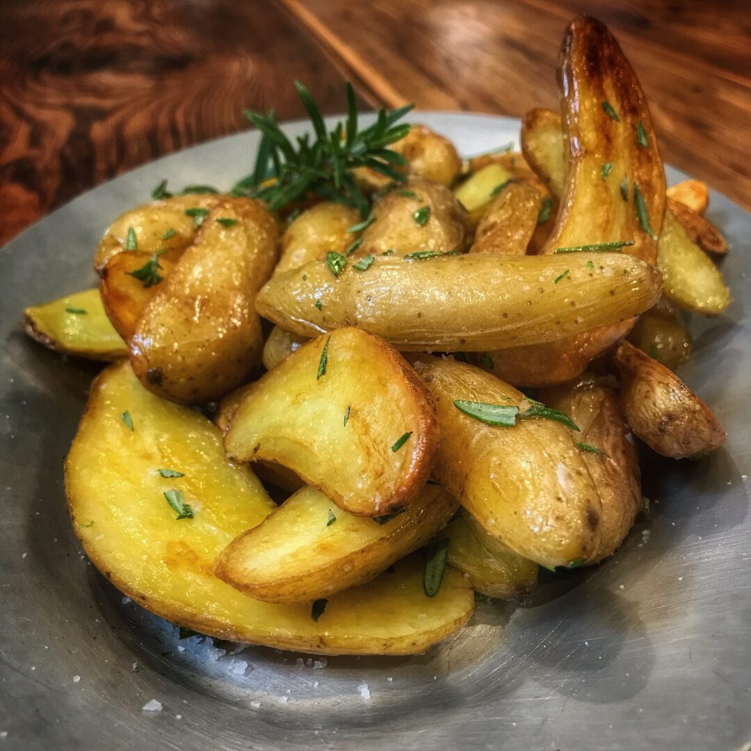Roasted potatoes with rosemary and thyme on a plate.