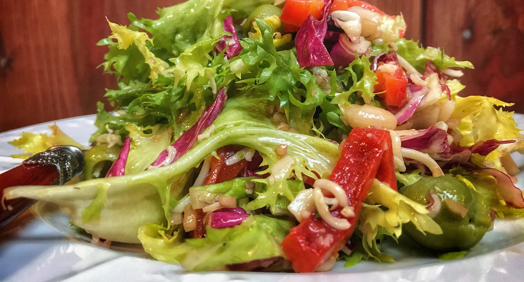 A plate with a salad and a fork on it.