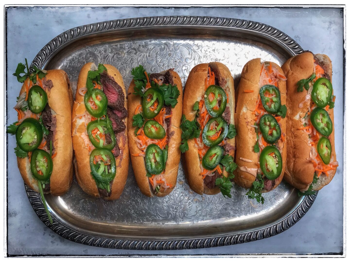 Hot dogs on a tray with jalapenos.