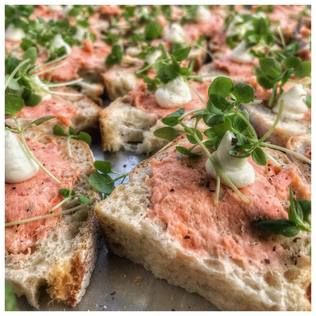A tray of bread with salmon and sour cream on it.