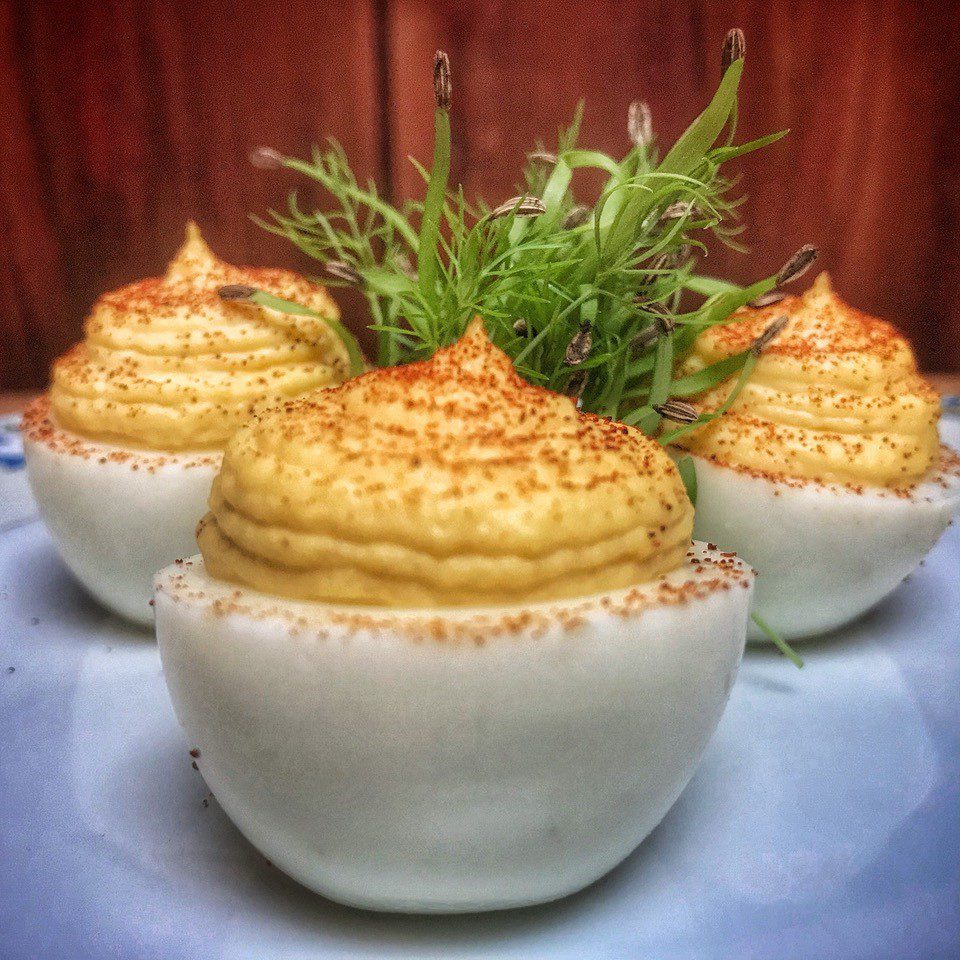 Deviled eggs on a white plate with a sprig of dill.
