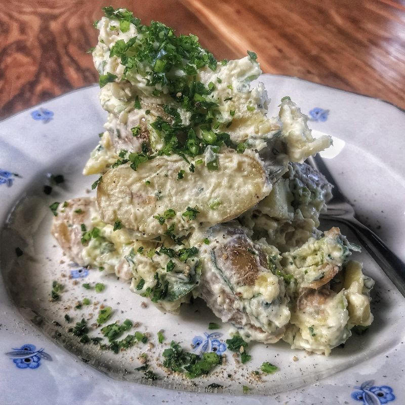 A plate of potato salad with parsley on it.