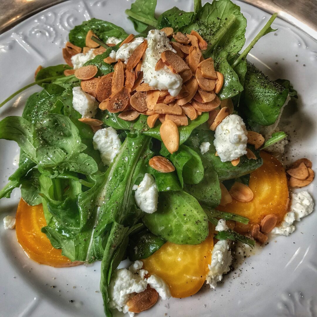 A plate topped with a salad with goat cheese and arugula.