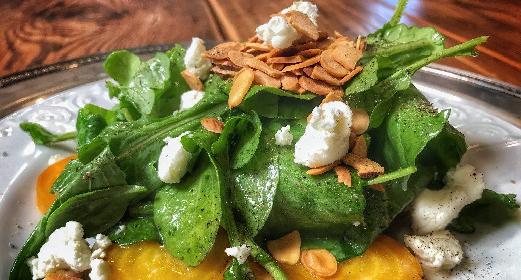 A plate topped with a salad with goat cheese and arugula.