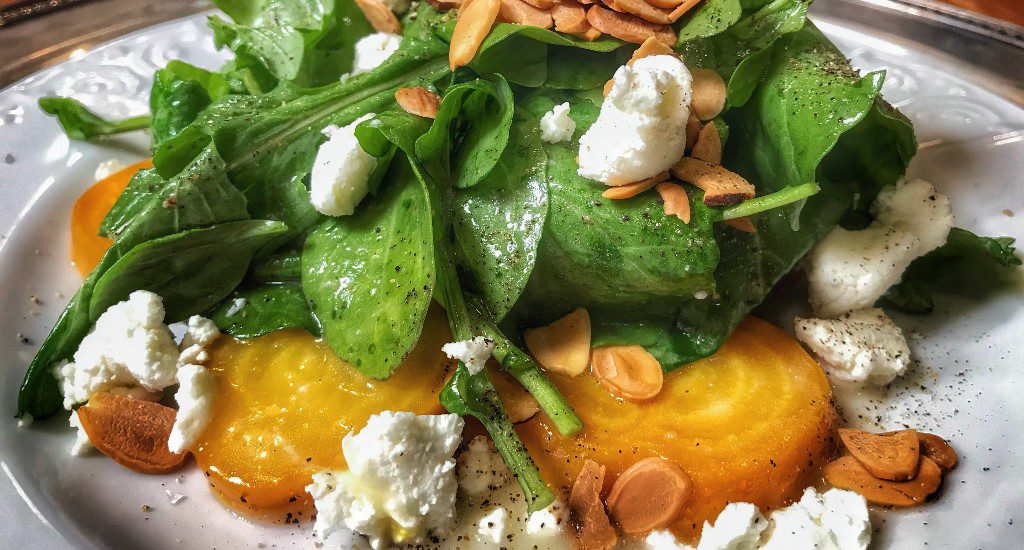 A plate with a salad with goat cheese and beets.