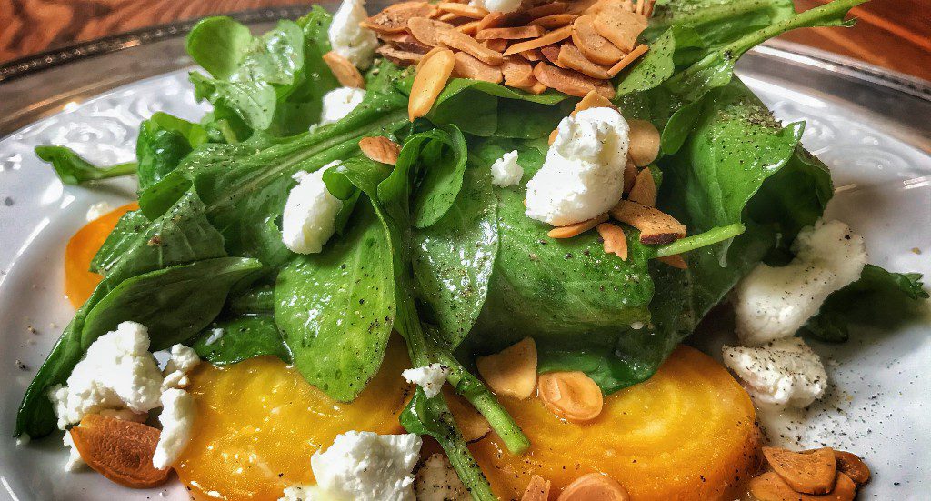 A plate with a salad with goat cheese and beets.