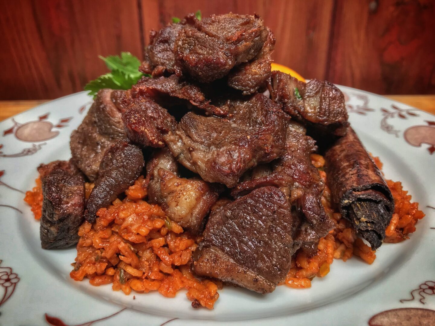 A plate of meat and rice on a wooden table.