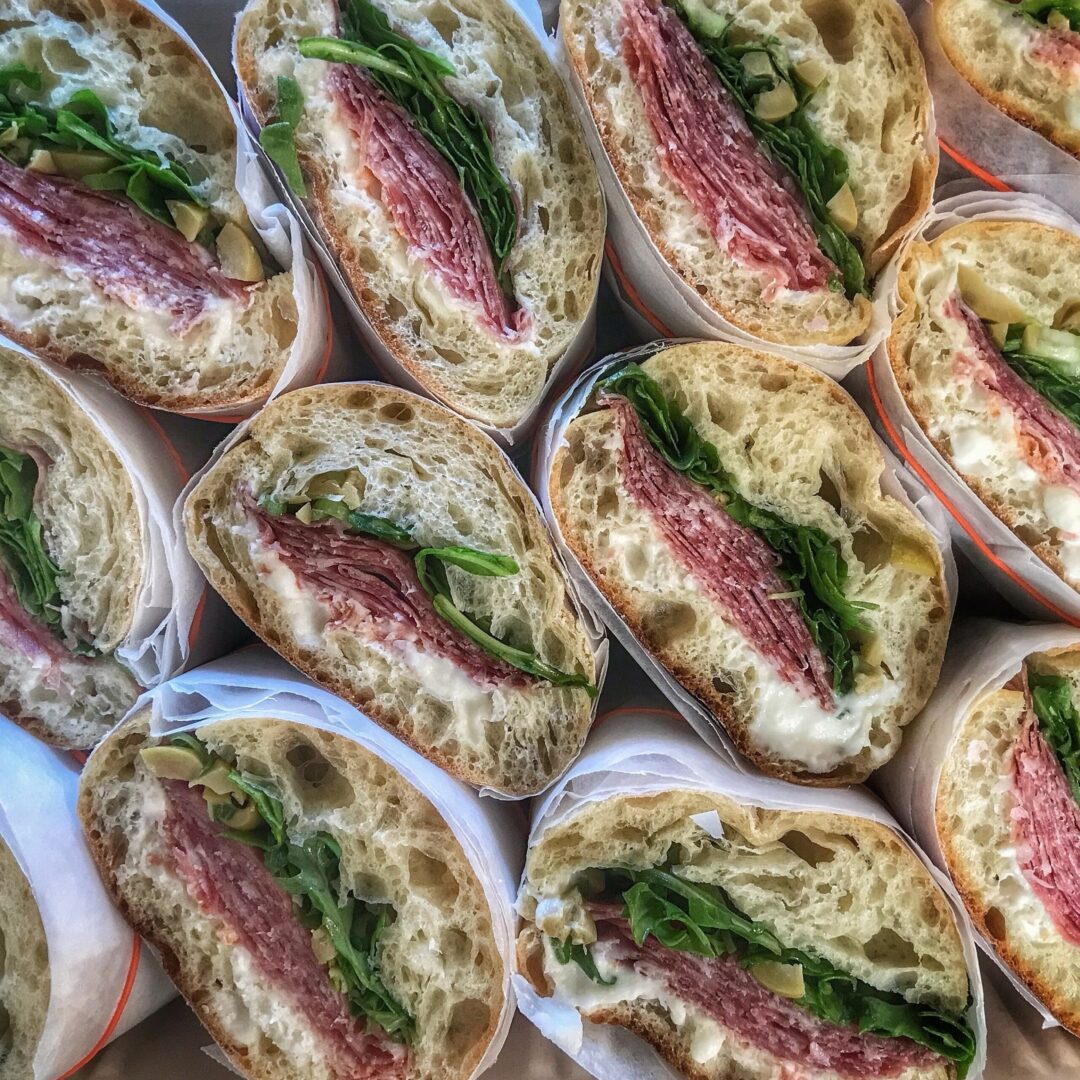 A bunch of sandwiches with meat and spinach in them.
