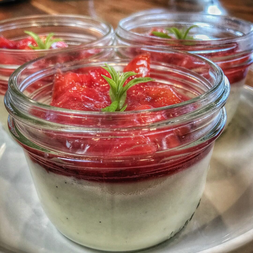 Three jars of yogurt with strawberries on a plate.