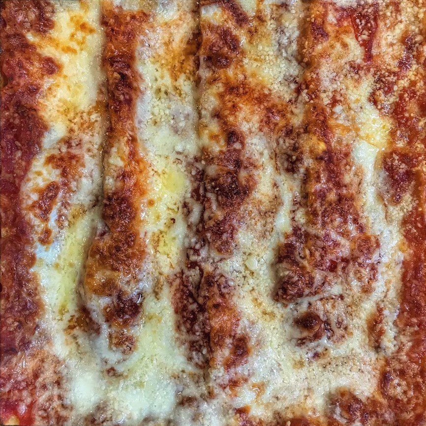 A close up of a square of lasagna with cheese on it.