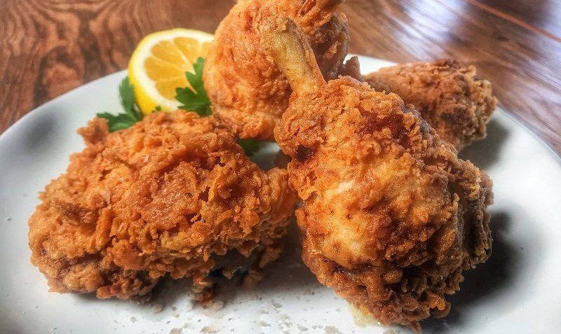 Fried chicken on a plate with lemon wedges.
