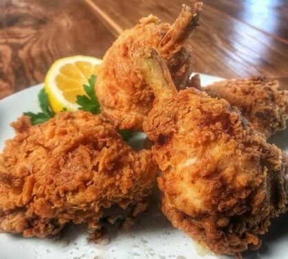 Fried chicken on a plate with lemon wedges.