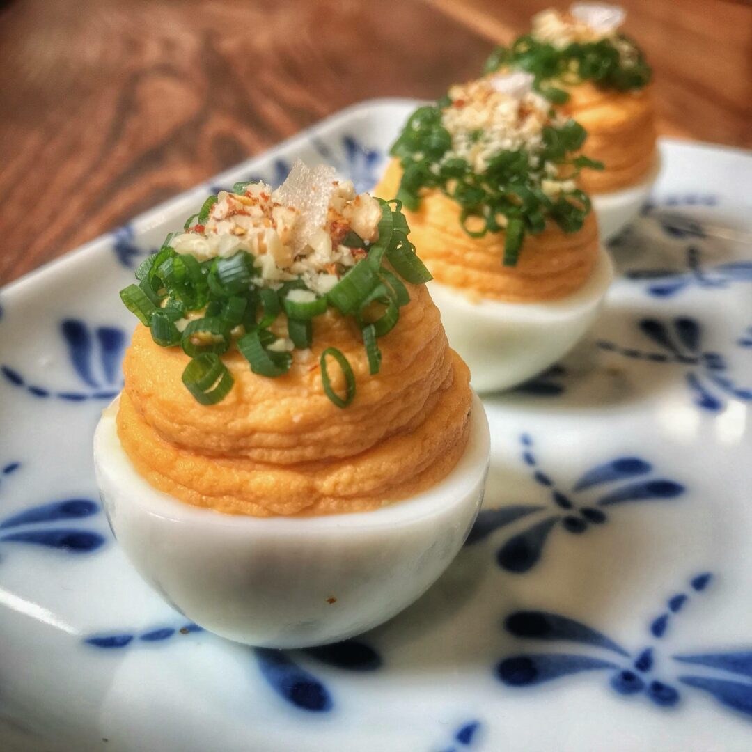 Three deviled eggs on a blue and white plate.