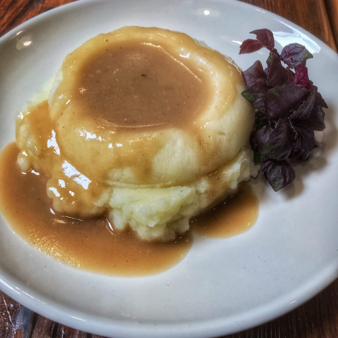 A plate with gravy and mashed potatoes.