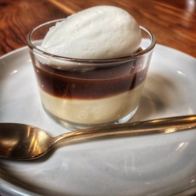 A dessert with whipped cream and a spoon on a plate.