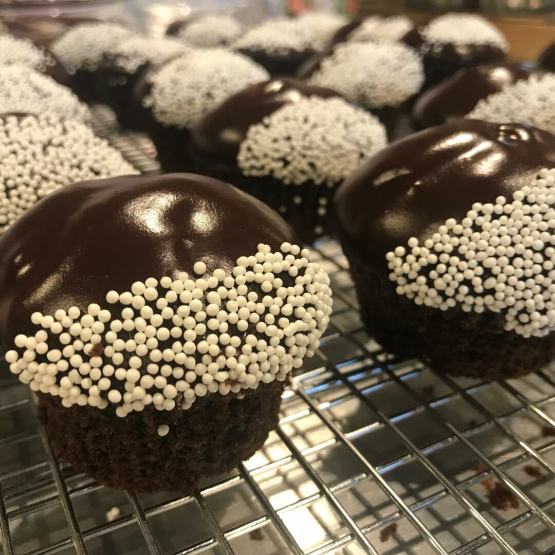 Chocolate cupcakes with white sprinkles on a cooling rack.