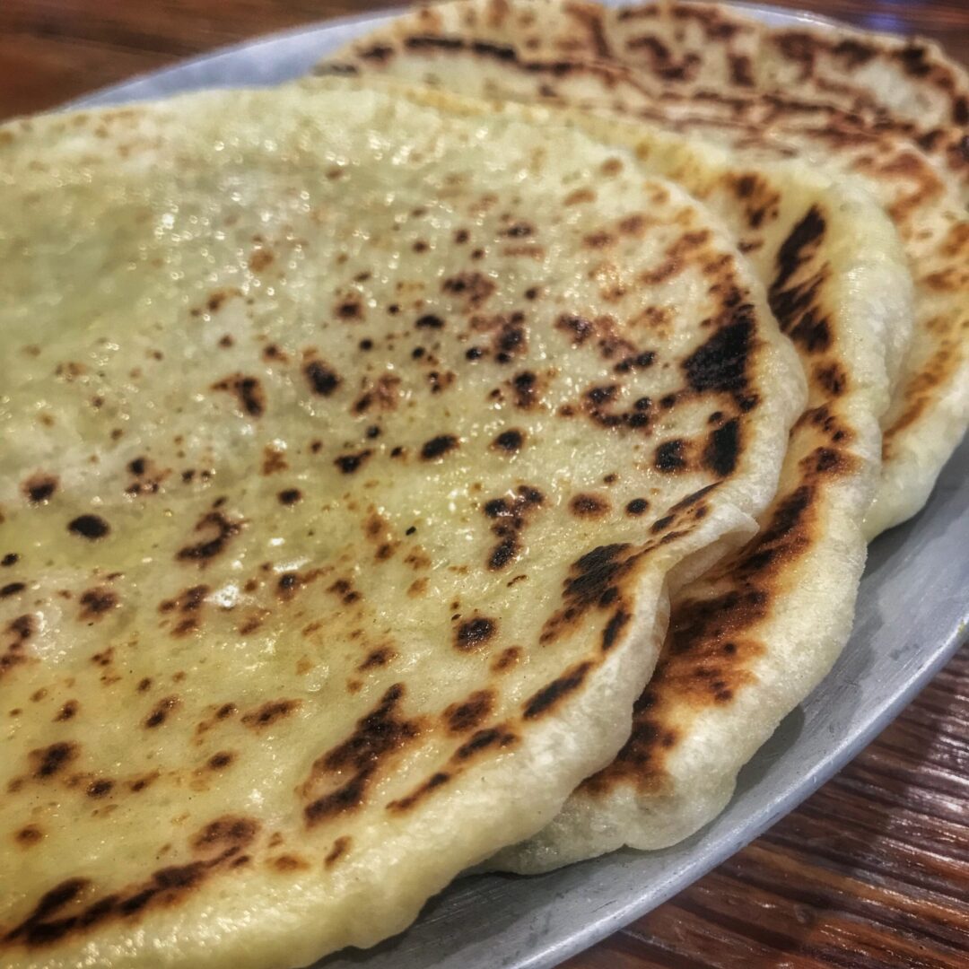 A plate of flatbreads on a wooden table.