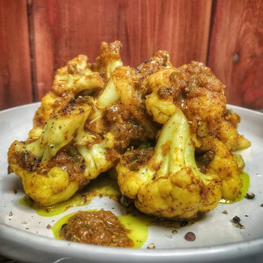 A plate of roasted cauliflower with sauce on it.