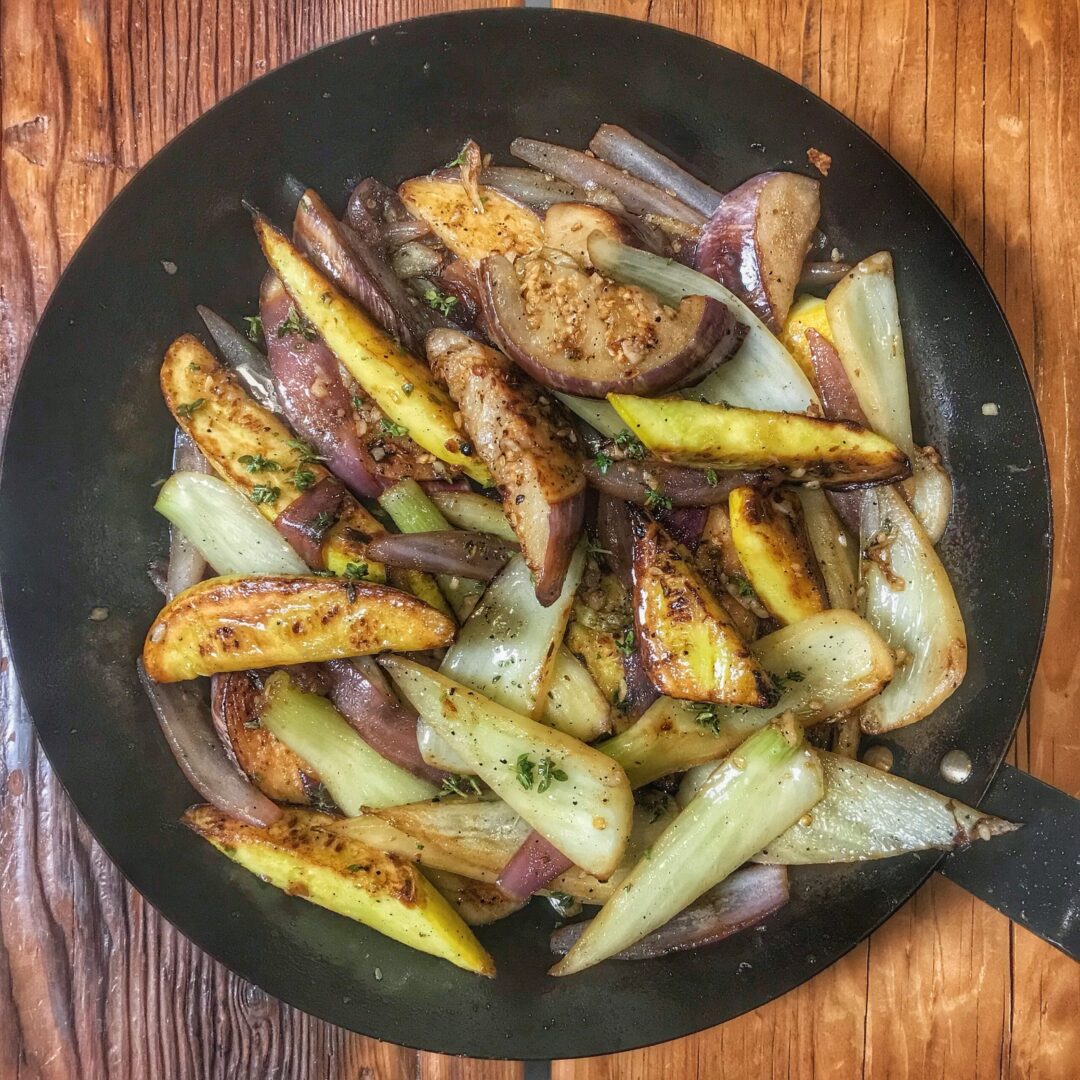 A frying pan full of sliced potatoes and onions.