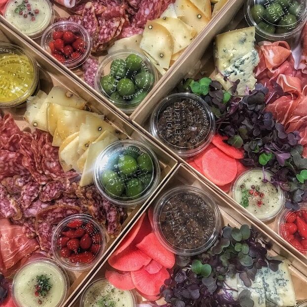 A variety of meats and cheeses in a wooden box.
