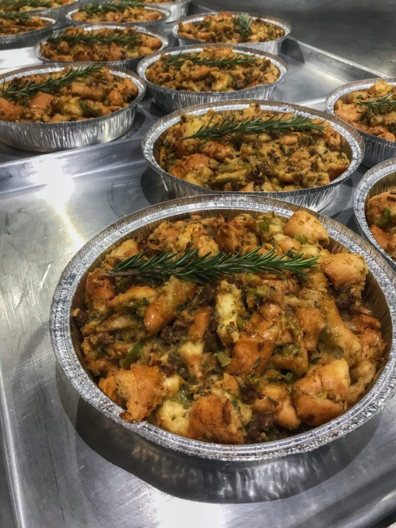 A tray of pies filled with stuffing and sprigs of rosemary.