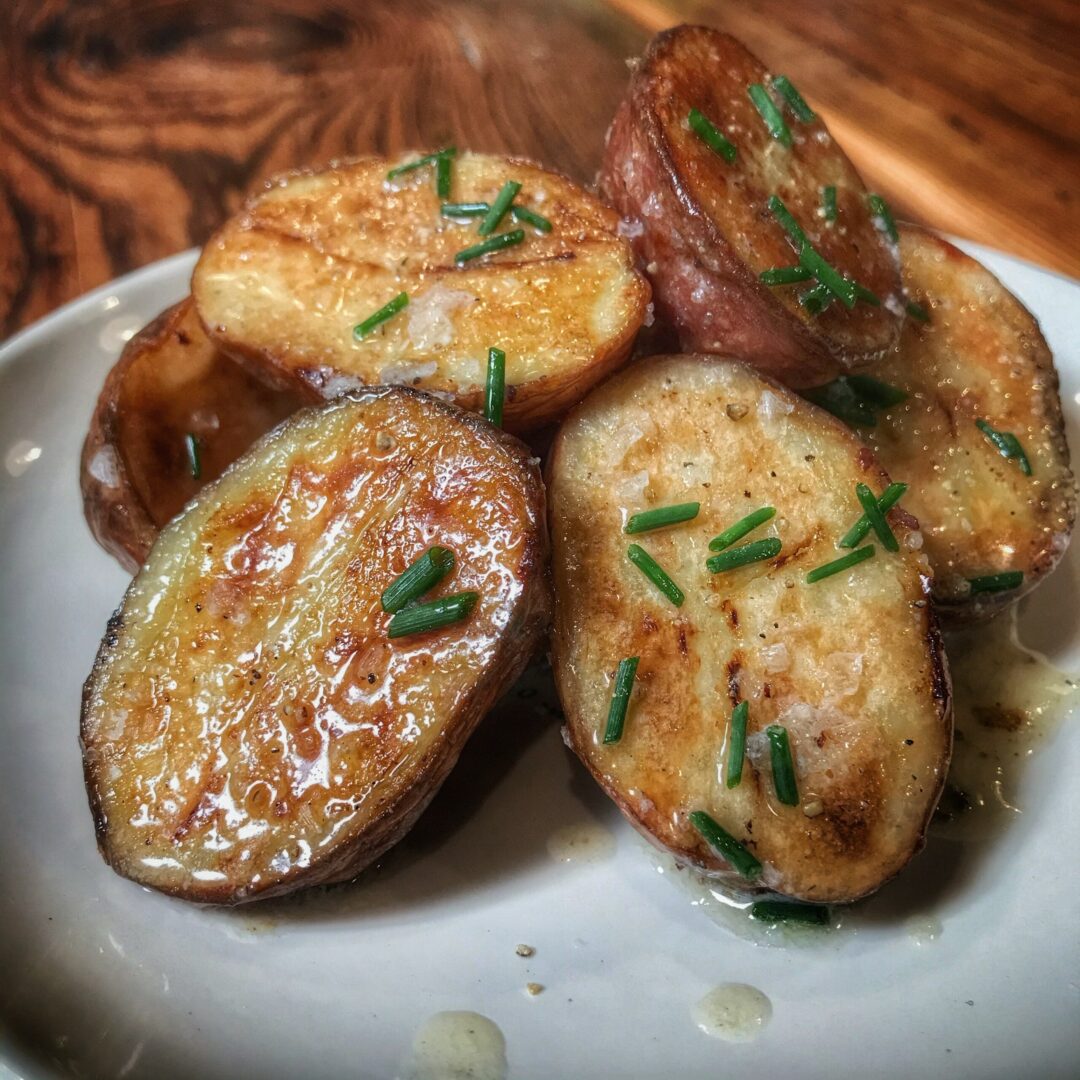Roasted potatoes with chives on a white plate.