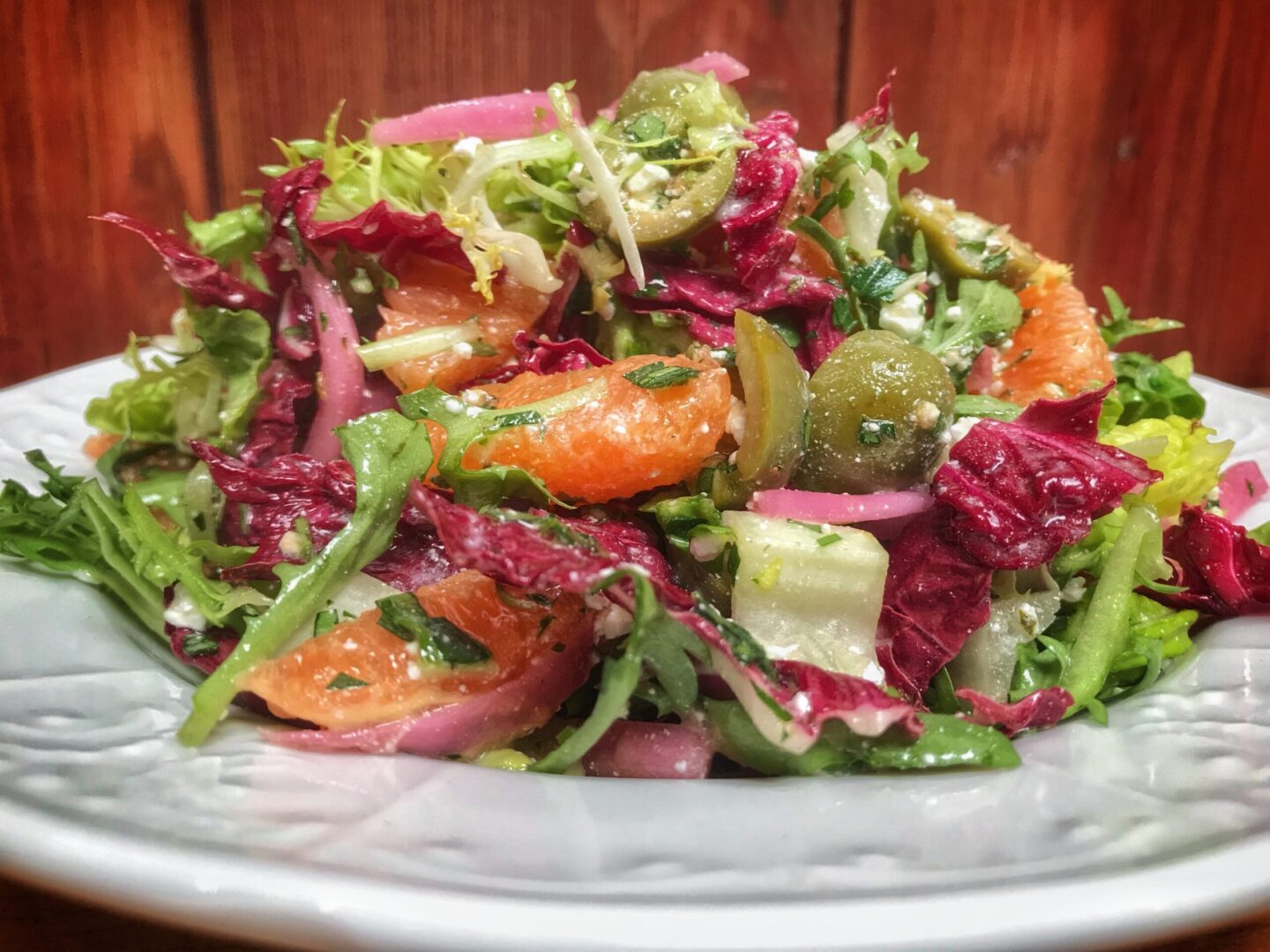 A salad with oranges, onions and lettuce on a plate.