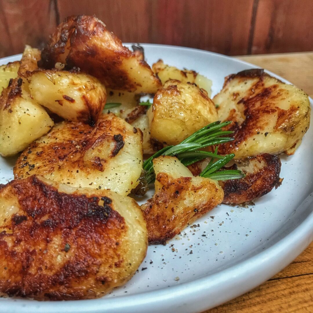 Roasted potatoes on a plate with rosemary sprigs.