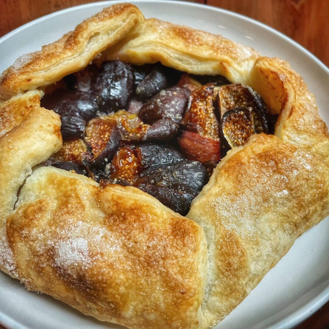 A pastry filled with figs and pistachios on a plate.