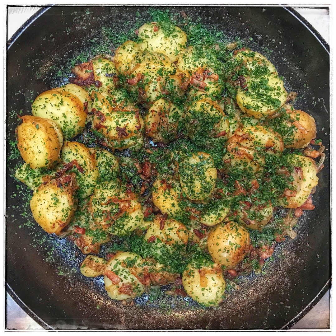 A frying pan filled with potatoes and herbs.