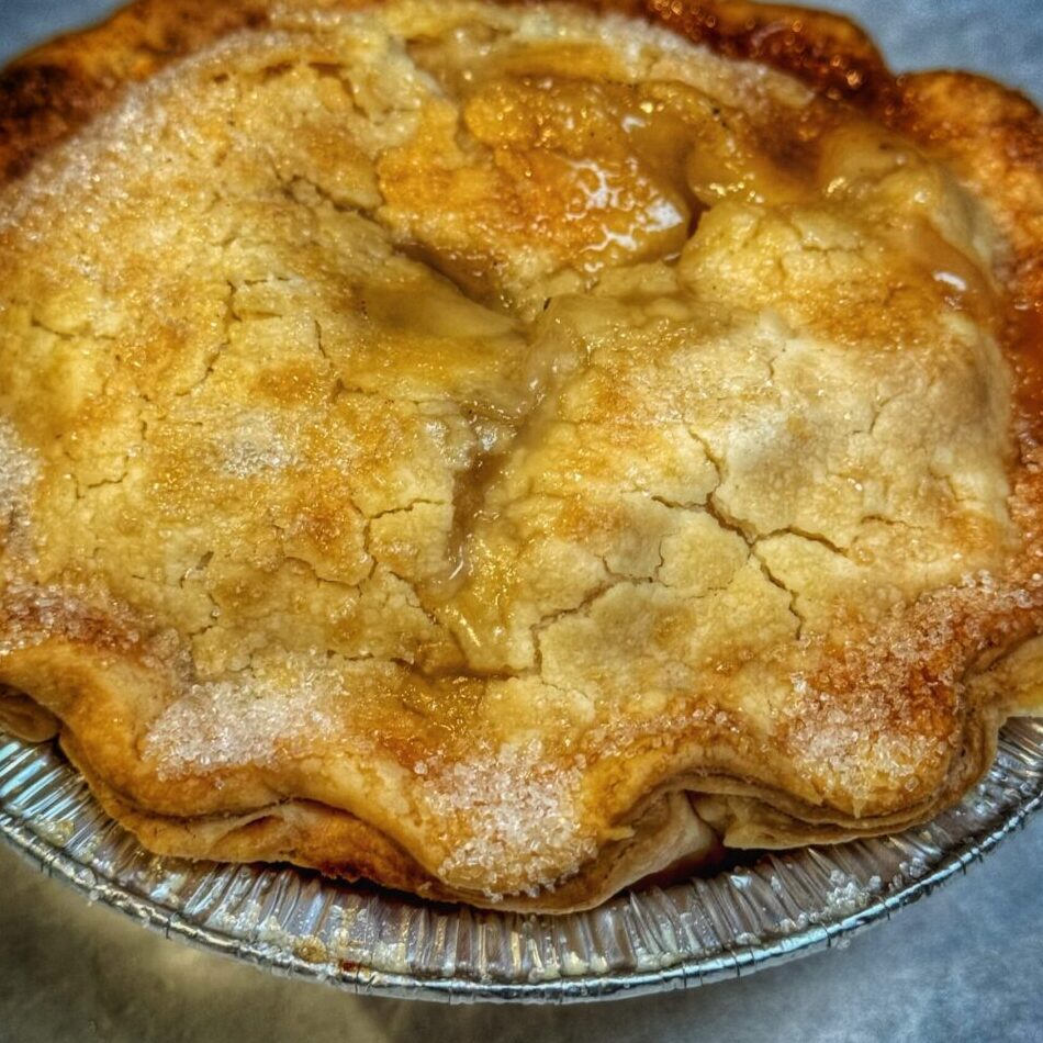 Freshly baked apple pie with a golden-brown crust in a tin plate.