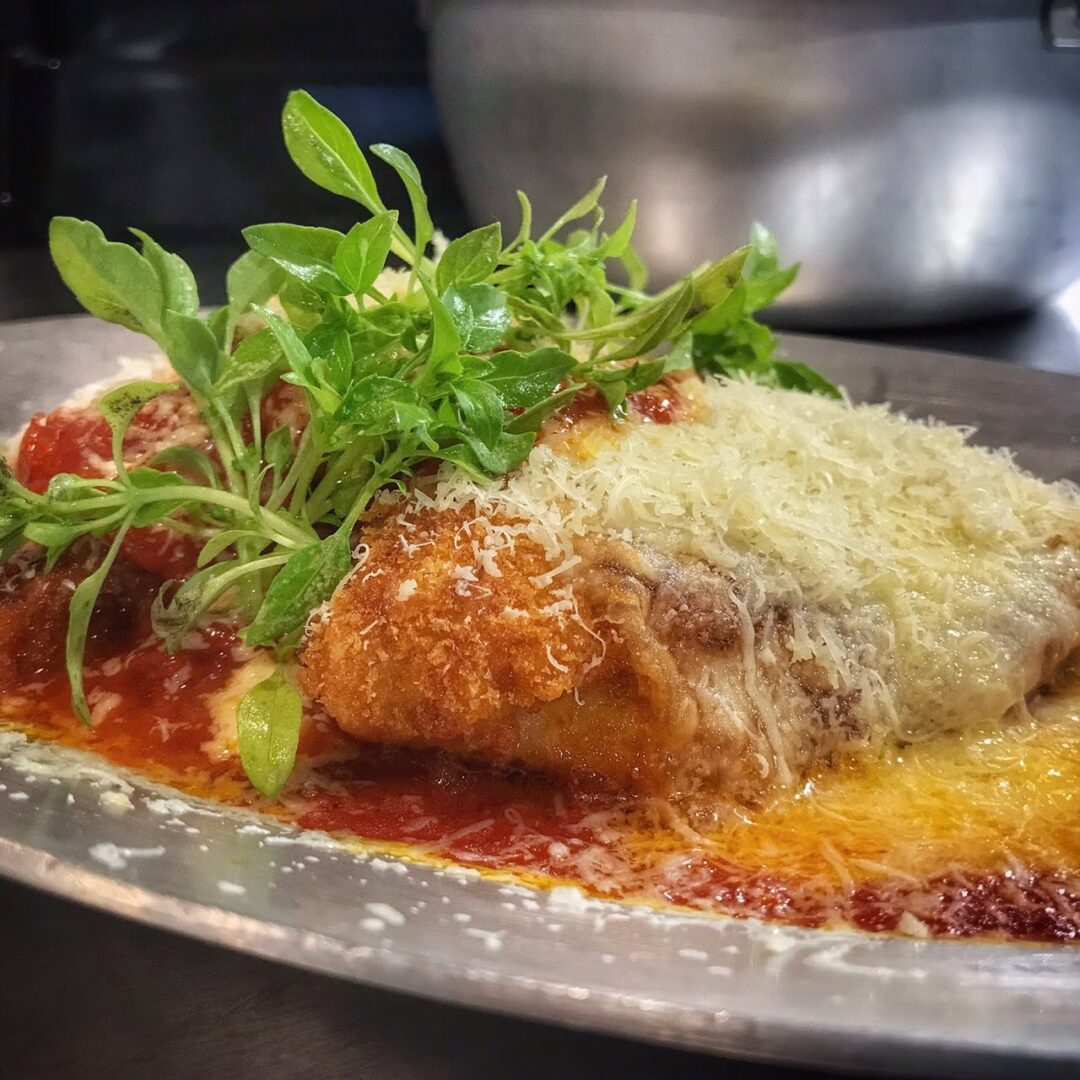 A plate of chicken parmigiana on a table.